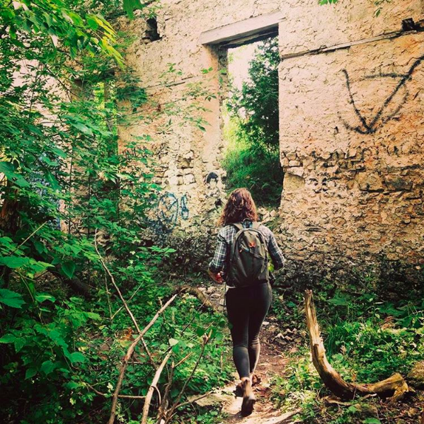 Jen Taylor walking amongst ruins overgrown by wildlife.
